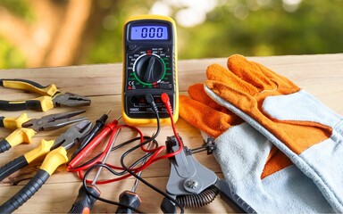Digital multimeter and instrument tools of electrician isolated on a blurred tree background.