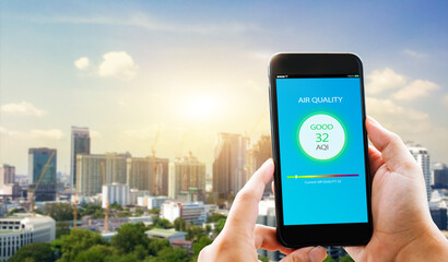 Air quality mobile app concept concept.close-up of man hands holding mobile phone on blurred cityscape as background