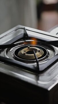 A close-up of a female hand lighting up a gas stove burner with a lighter