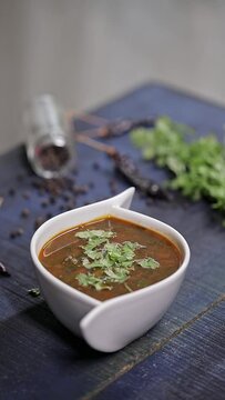 Female hand garnishing moringa leaf curry with coriander leaves in a white bowl