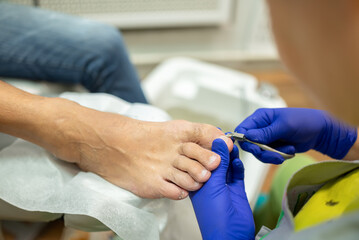 concept of male pedicure, cosmetologist makes classic pedicure for an elderly male client.