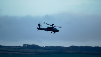 Fototapeta na wymiar British army Boeing Apache Attack helicopter gunship (AH64E AH-64E ArmyAir606) in low level flight, Wiltshire UK