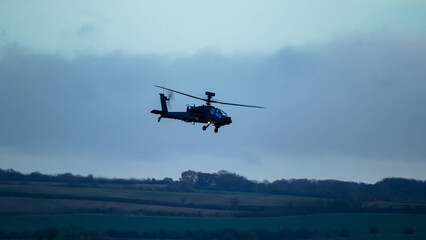 Fototapeta na wymiar British army Boeing Apache Attack helicopter gunship (AH64E AH-64E ArmyAir606) in low level flight, Wiltshire UK
