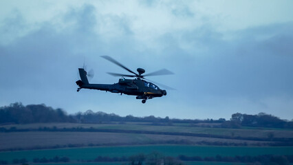 British army Boeing Apache Attack helicopter gunship (AH64E AH-64E ArmyAir606) in low level flight,...