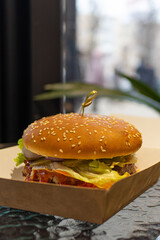 Holding a hamburger in his hands. Delicious appetizing burger.Fast food cafe.American food.Burger recipe.Cafe menu.Appetizing 
feed.Home delivery of food.food in a box.juicy burger.client.
eating.