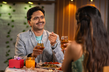 Shoulder shot, curious husband talking with wife during candle light dinner at anniversary or birthday celebration - concept of romantic date night, affection and companion
