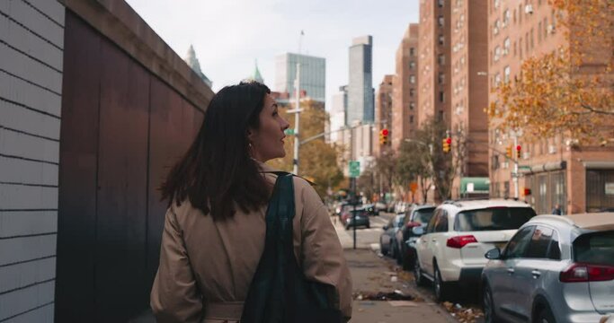 Female tourist walks around urban streets of New York City with skyscrapers in the background