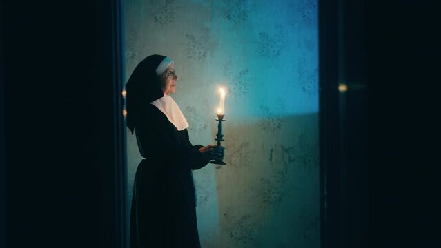 Possessed nun ghost holding burning candles and walking haunted house, magic