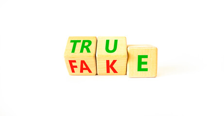 Fake or true symbol. Turned wooden cubes and changed the word fake to true or vice versa. Beautiful white table, white background, copy space. Business and fake or true concept.