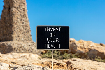 Invest in your health symbol. Concept word Invest in your health on beautiful black chalk blackboard. Beautiful red stone blue sky background. Invest in your health concept. Copy space.