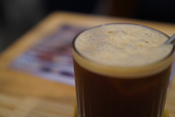 Frothy Coffee in a Tall Glass on Wooden Table
