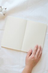 Cozy reading a book in bed. Hand on a book on a white sheet