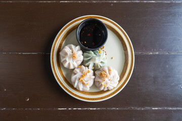 Steamed chives dumplings with black soy source on plate as Chinese traditional food. Top view or...