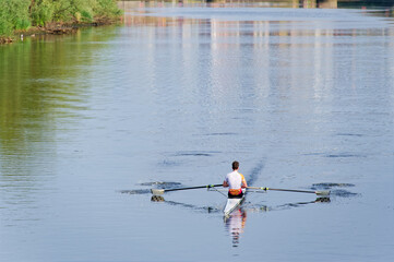 Man training on canoe to practise rowing during early morning on river