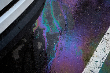 Leakage of oil or gasoline from the car on the asphalt in the parking lot.