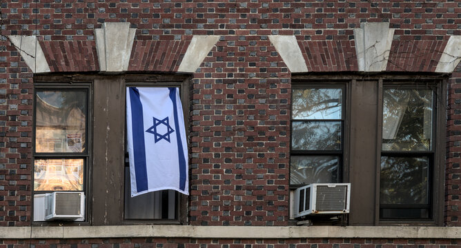 israeli flag hanging in the window of an apartment building in brooklyn, new york (support for israel from abroad) blue and white banner with star of david