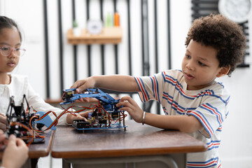Happy African American kid boy studying with electric robot and friend in classroom	