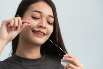 Asian woman braces using dental floss. Teeth braces on the white teeth of women to equalize the...