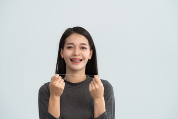 Asian woman braces using dental floss. Teeth braces on the white teeth of women to equalize the teeth. Bracket system in smiling mouth, close up photo teeth, macro shot, dentist health concept.