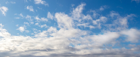 White curly clouds in the blue sky in sunny weather