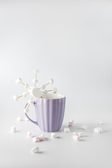 A purple mug with hot coffee and marshmallows. Cup with marshmallows in snowflake shapes.