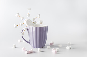 A purple mug with hot coffee and marshmallows. Cup with marshmallows in snowflake shapes.