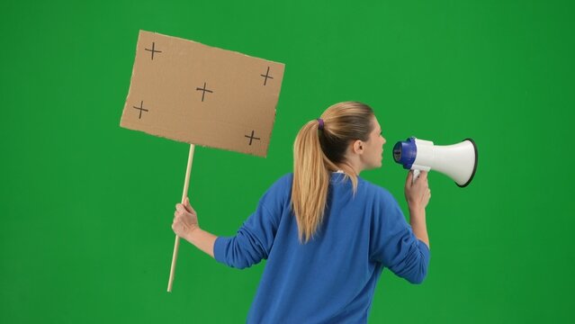 Woman facing away from camera speaking into a megaphone and holds a blank placard in her hand. Back view of a woman with a mouthpiece and placard on a green screen close up. Protest action. - Powered by Adobe