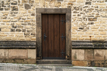 The door of a medieval gothic building made out of wood and metal.