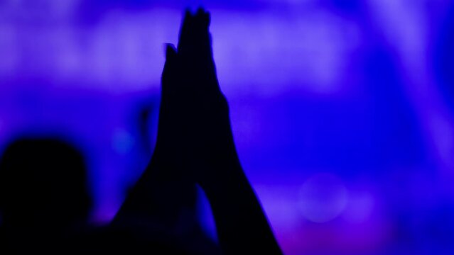 Close-up of hands at mass event. Slow motion. A woman claps her hands.