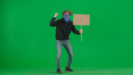 Male activist with face covered by scarf holding a blank sign. Male protester on green screen....