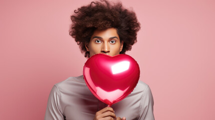 Fototapeta na wymiar Man holding heart shaped balloon against pink background