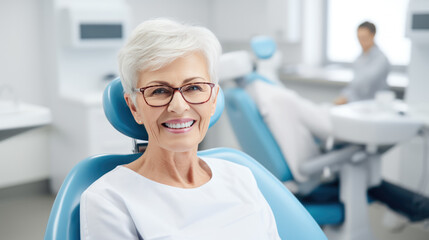 Fototapeta premium Elderly female patient with white hair, smiles happily while sitting in a dental chair
