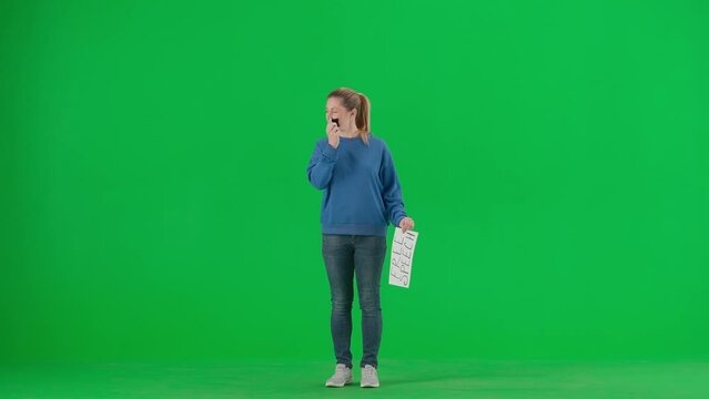 A woman with her mouth taped with black tape holds a poster with the inscription free speech. Protestant woman removing tape from her mouth on green screen. Concept of freedom of speech.