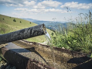 Water spring with crystal clear mountain water in the alps. Alpine water source.