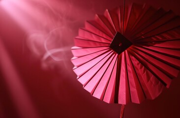 a pink origami fan hangs on a red background