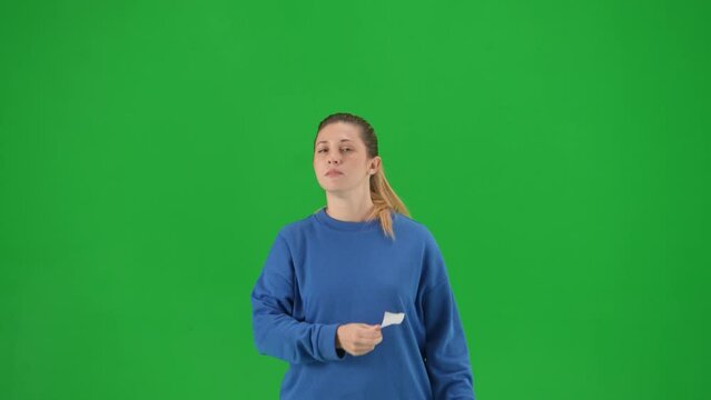 A woman with her mouth taped with black tape holds a poster with the inscription free speech. Protestant woman removing tape from her mouth on green screen close up.