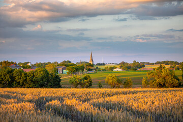 Village français et son clocher à la campagne au milieu des champs de blé.
