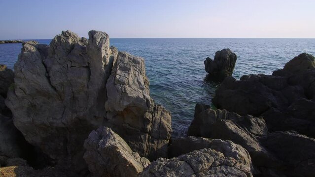 Beautiful view of the Aegean Sea through the rocky shore of the old Greek village of Loutra at sunset