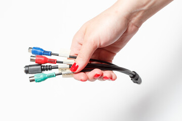 Different color connectors for video equipment in a girl's hand with red manicure on a white background