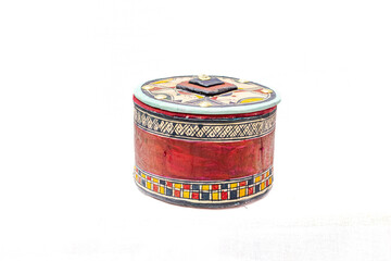 A hand made circular box closed with its lid. With lots of patterns and colors. Squares, stripes...