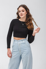 girl model in black shirt and blue trousers posing relaxed in studio