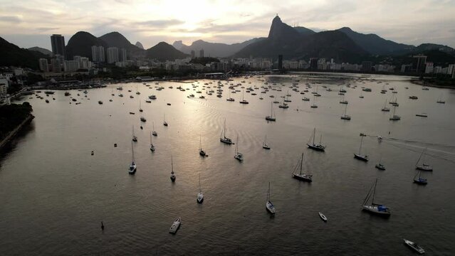 Aerial drone approaching Botafogo Bay in Rio de Janeiro, Brazil at sunset with iconic Christ the Redeemer Statue visible - UNESCO World Heritage Site