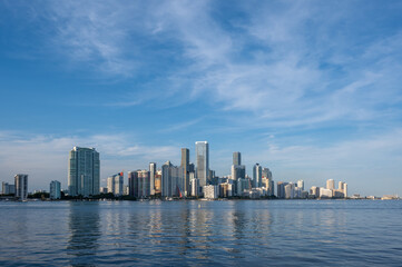 City of Miami, Florida skyline reflected in calm water of Biscayne Bay at sunset on clear sunny December afternoon.