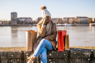 Woman in warm clothing with shopping bags is worried because she spent too much money. Toned image.