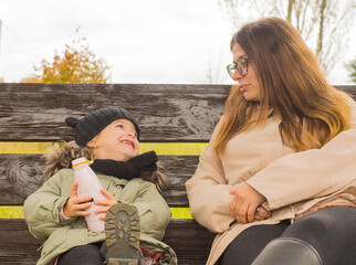 mother and child have a snack on a bench