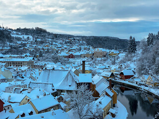 Winter view of Czech Krumlov. Český Krumlov, UNESCO. Historical town with Castle and Church at sunrise. Beautiful winter morning landscape with an illuminated monument. Snowy cityscape scene from the 