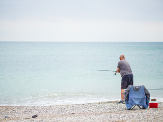 Fisherman with a fishing rod in the ocean early in the morning catches fish