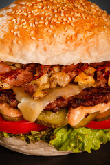 Burger with bacon onions tomatoes cucumber lettuce and souces. Abstract fast food photo.