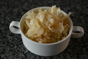 fermented cabbage, fermented white cabbage in a white plate on a gray background