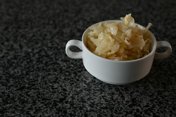 fermented cabbage, fermented white cabbage in a white plate on a gray background